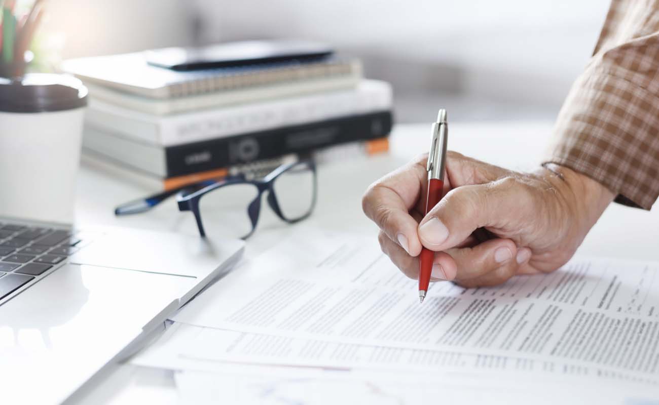 Person Reviewing Documents and Taking Notes